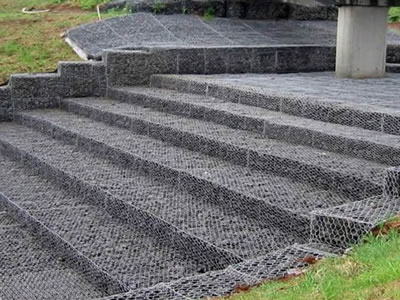 Some stones are placed in gabion mattress as steps under bridge.