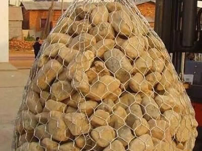 A large bag made of hexagonal wire mesh takes rocks inside.