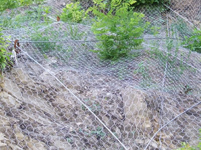 The picture shows proactive rockfall netting, where big opening mesh is above small opening mesh, with steel wire rope anchoring them.