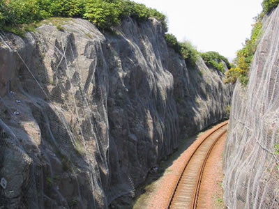 Rockfall netting hangs on the mountain beside the railway.