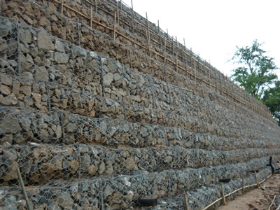 Gabion basket and rocks make a retaining wall to deter something or protect something.