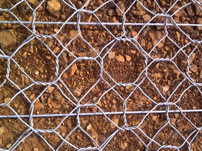 Two layers of hexagonal wire mesh is overlapped together on a soil road.